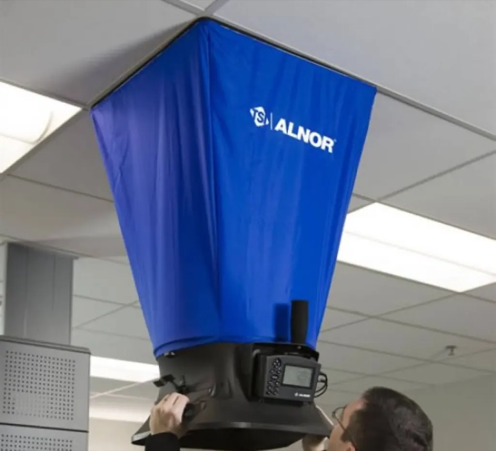 Air balancing a ceiling diffuser with a calibrated flow hood