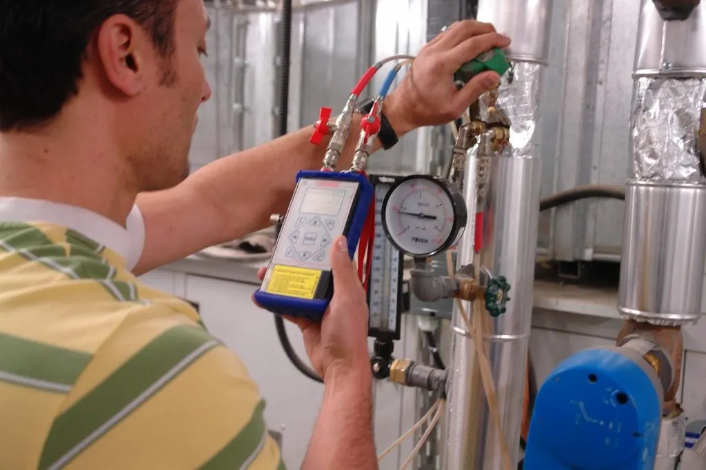Technician balancing a hydronic water system with a differential pressure meter